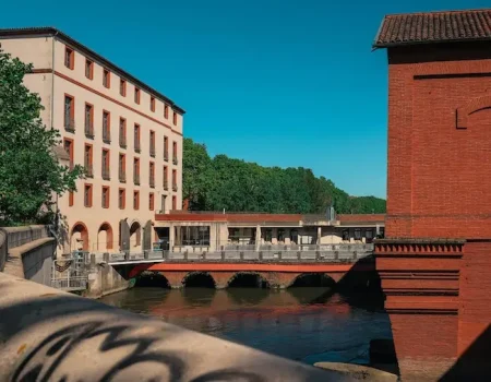 Le charme du patrimoine historique de Blagnac avec ses bâtiments traditionnels en briques roses au bord de l'eau.